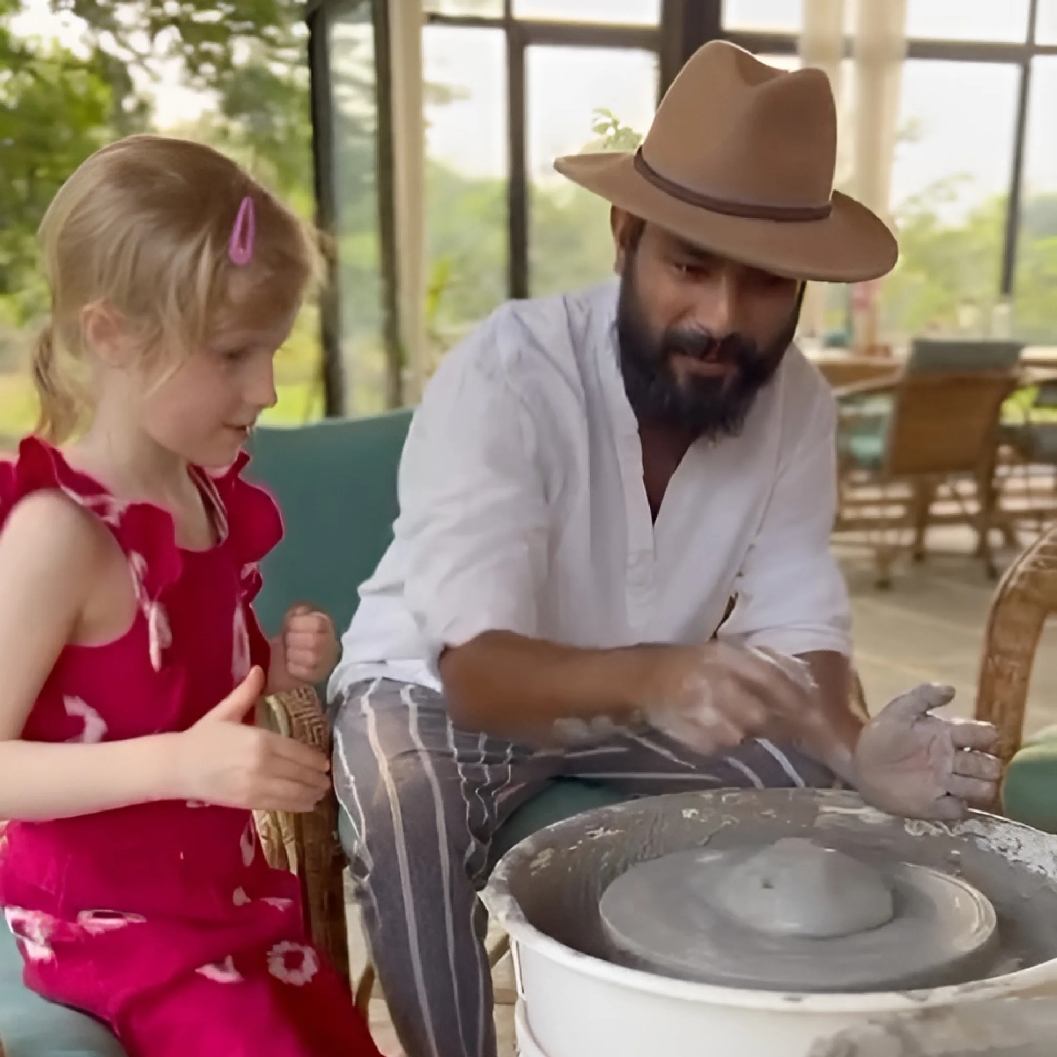 Man teaching pottery to a young girl in a pottery workshop inside the Farm.