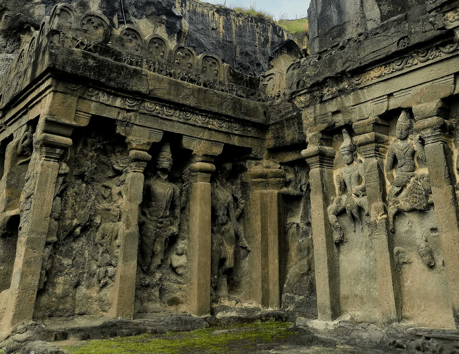 Ancient rock-cut temple adorned with intricate carvings and weathered sculptures