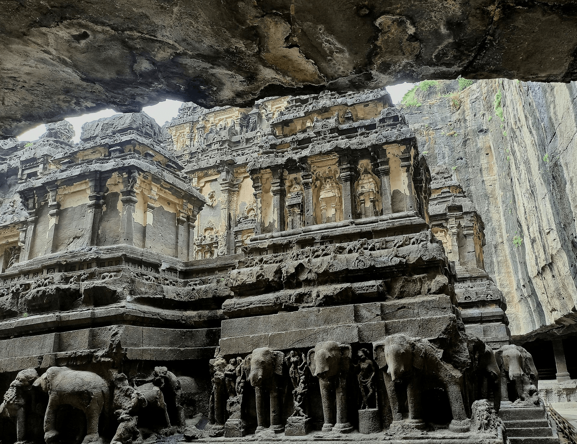 Intricately carved stone temple with elephant sculptures, framed by rugged cliffs.