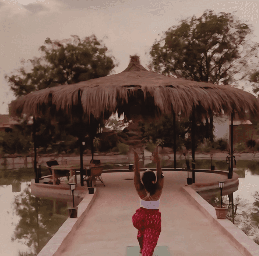 Experiences 3 A woman practicing yoga on a serene bridge at Dhyaana Farms during sunset